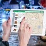 Hands using a digital map on a tablet in an urban setting at night, illustrating navigation and technology.