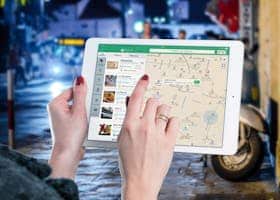 Hands using a digital map on a tablet in an urban setting at night, illustrating navigation and technology.